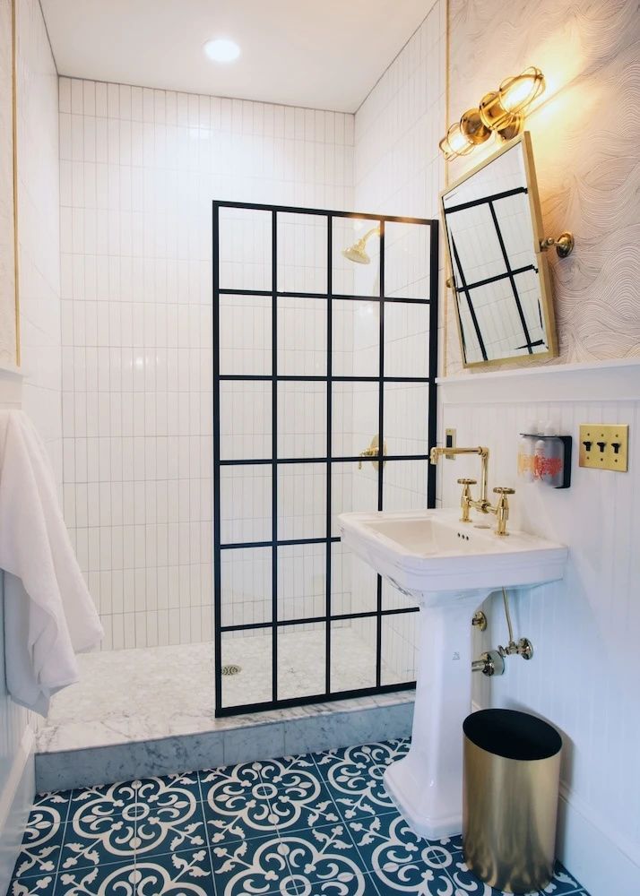 Badezimmer mit schwarzer Duschabtrennung im Sprossendesign und Standwaschbecken.