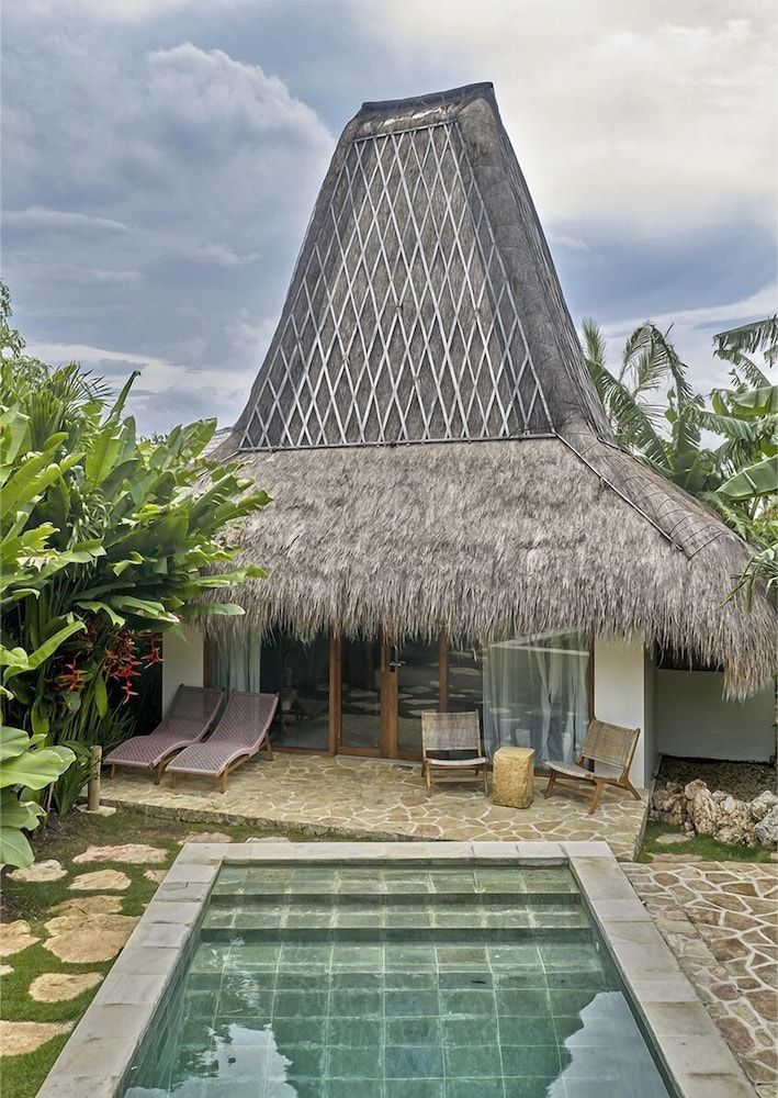 Bungalow mit Reetdach, Terrasse mit Liegestühlen und einem kleinen Tauchbecken davor.