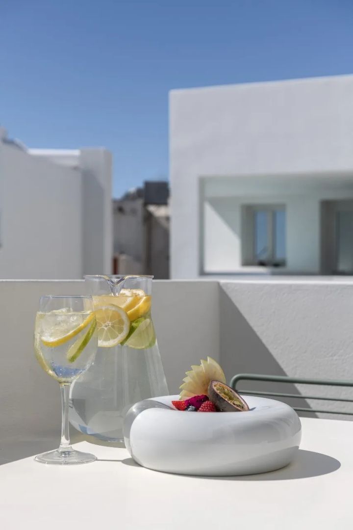 Glaskaraffe mit Zitronenwasser und Obstschale auf einem Tisch auf der Balkonterrasse.
