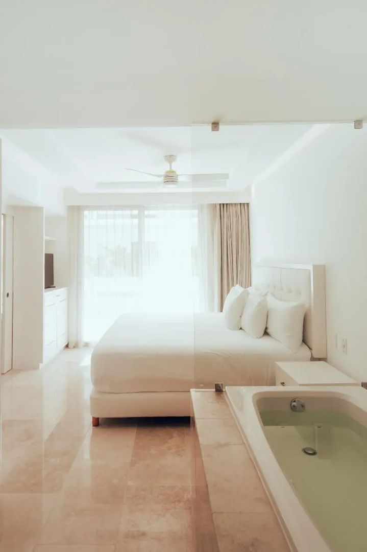 Helles Hotelzimmer mit großem Doppelbett, Deckenventilator und integrierter Badewanne.