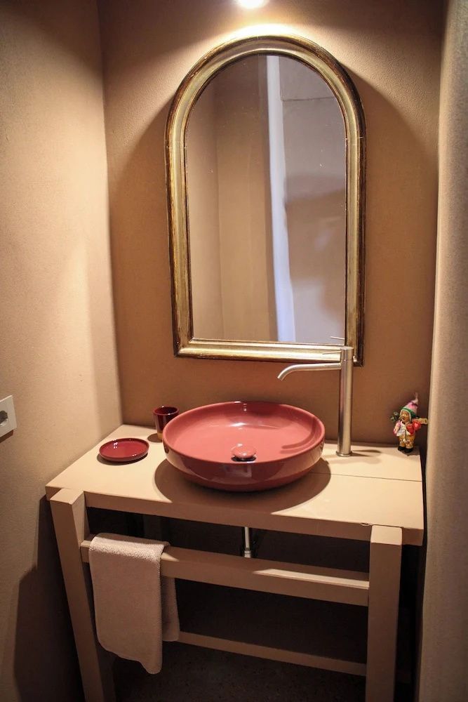 Waschtisch im Badezimmer mit einem runden terrakottafarbenen Waschbecken und Spiegel.