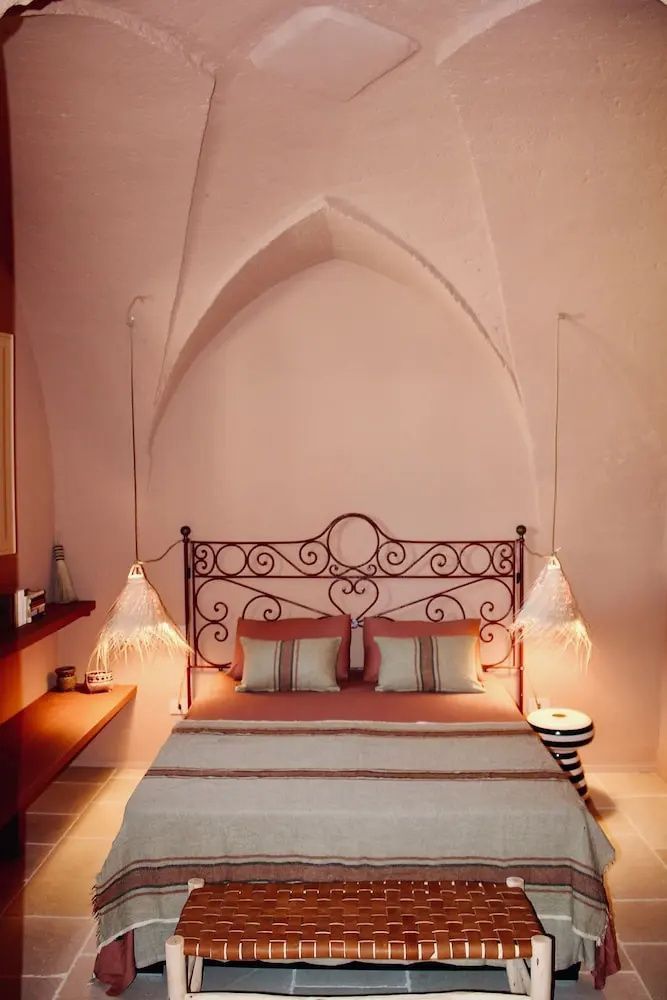 Doppelbett unter einem gewölbten Spitzbogen mit zwei hängenden Nachttischlampen.