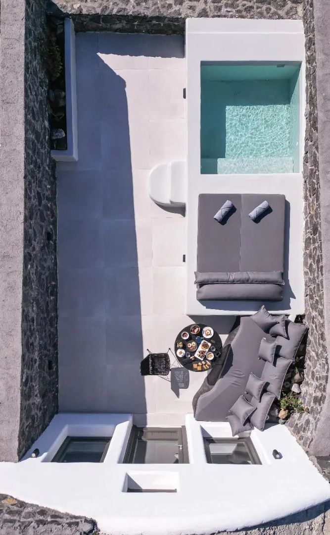 Draufsicht auf einen gepflasterten Innenhof mit einem kleinen Pool, Sonnenliege und Loungesofa.