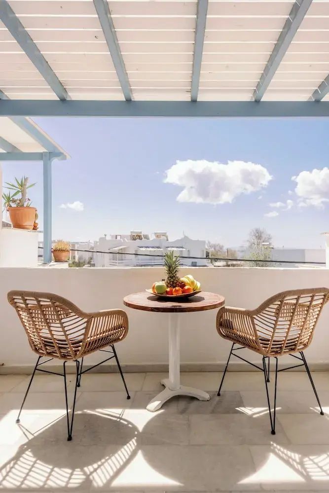 Balkon mit zwei Stühlen aus Geflecht, einem Tisch mit Obstschale und Weitblick.