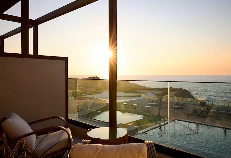 Blick vom Balkon bei Sonnenuntergang auf die Poolanlage und das Meer.