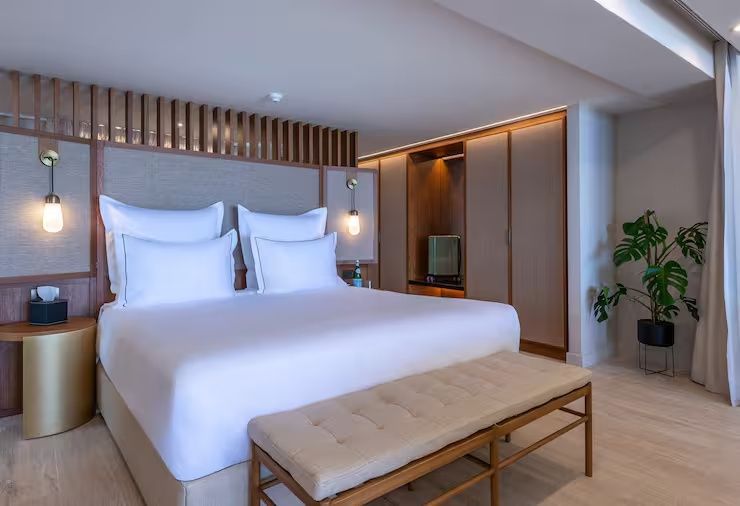Helles Schlafzimmer mit großem Doppelbett, weißer Bettwäsche und hölzernem Einbauschrank.