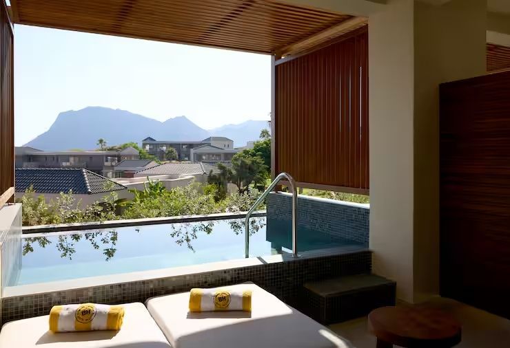 Überdachte Terrasse mit Liegestühlen und einem kleinen Pool sowie Blick auf die Berge.