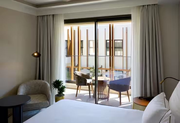 Blick aus dem Hotelzimmer auf die verglaste Balkontür mit Sitzplatz.