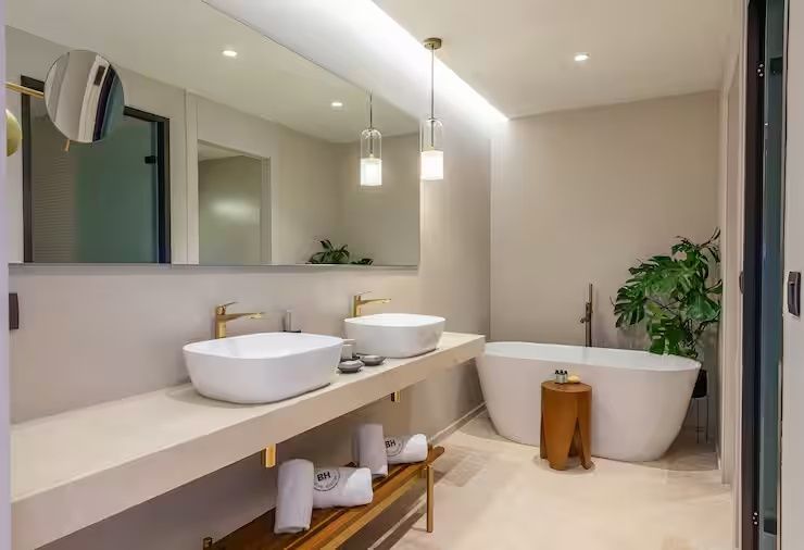 Badezimmer mit zwei Aufsatzwaschbecken, großem Spiegel und einer freistehenden Badewanne.