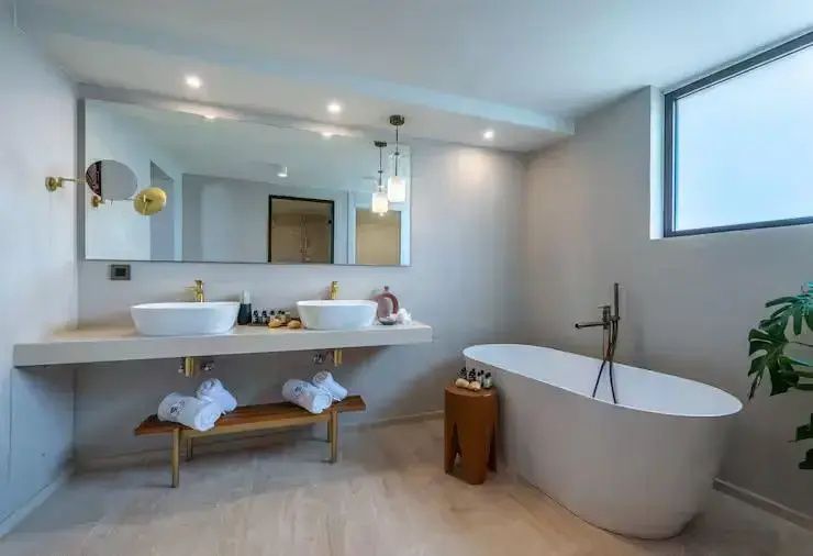 Badezimmer mit freistehender Wanne, Spiegel und Doppelwaschtisch auf Holzkonsole.