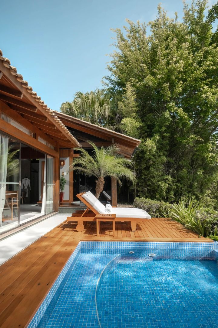Privater Pool mit blauen Fliesen auf einem Holzdeck neben der Villa mit Liegestuhl.