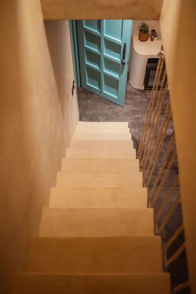 Blick von oben auf eine helle Treppe im Zimmer mit Blick auf eine blaufarbene Tür.