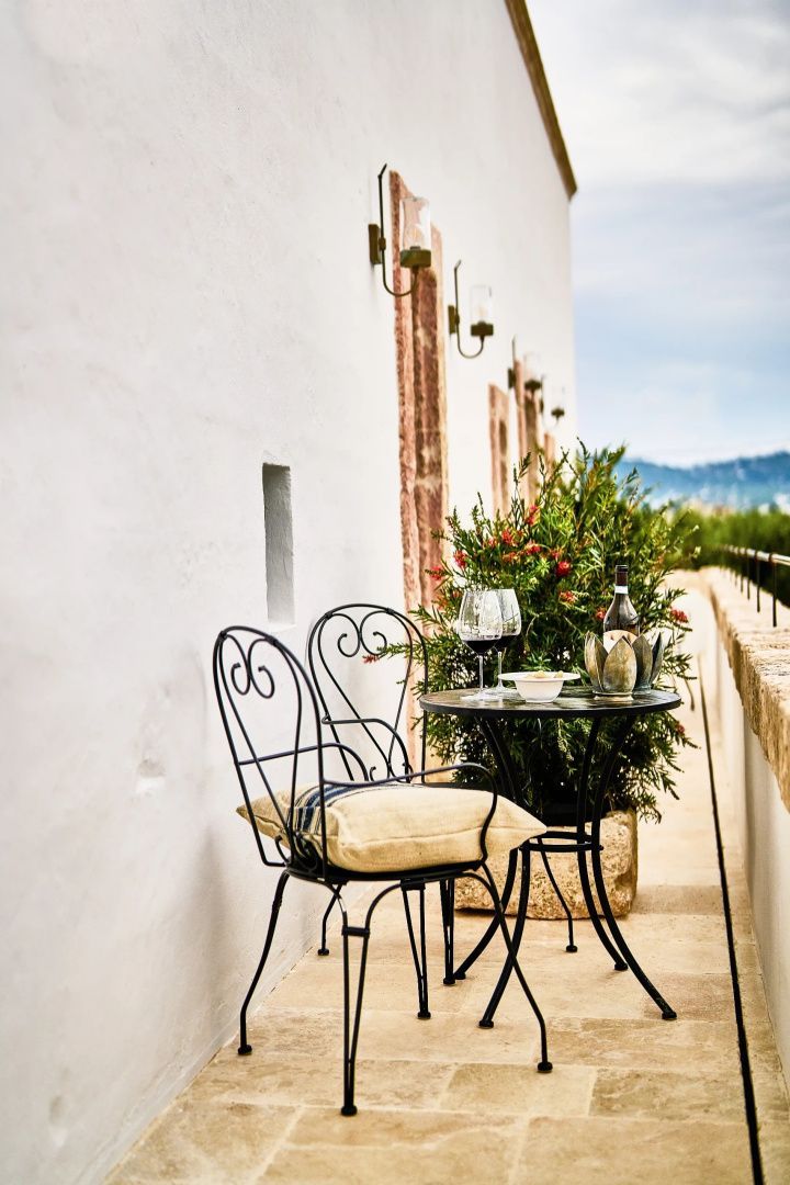 Sitzgruppe aus Schmiedeeisen auf einer schmalen Terrasse mit Blick auf die umliegende Landschaft.