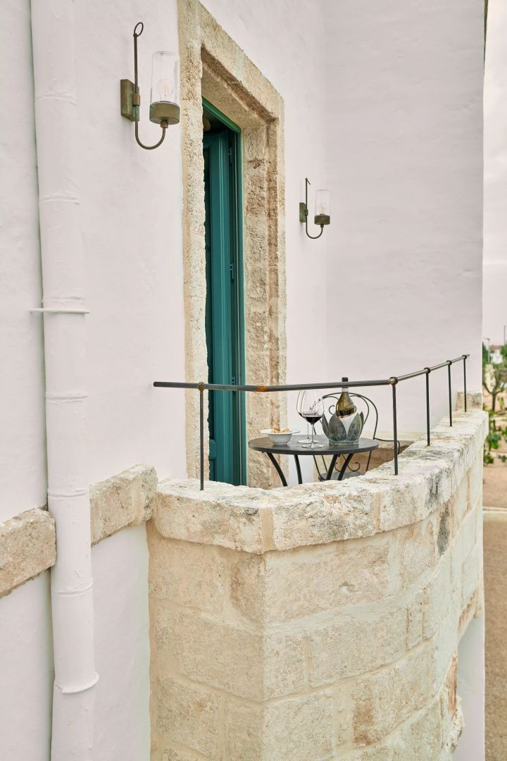 Kleine Steinbalustrade auf einem Balkon mit Bistrotisch, Weingläsern und Ausblick.