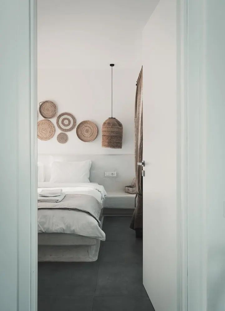 Blick durch eine geöffnete weiße Tür auf ein Doppelbett mit Flechtdekoration.