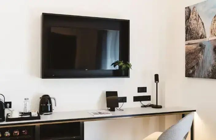 Schreibtischbereich im Zimmer mit an der Wand montiertem Fernseher und Wasserkocher.