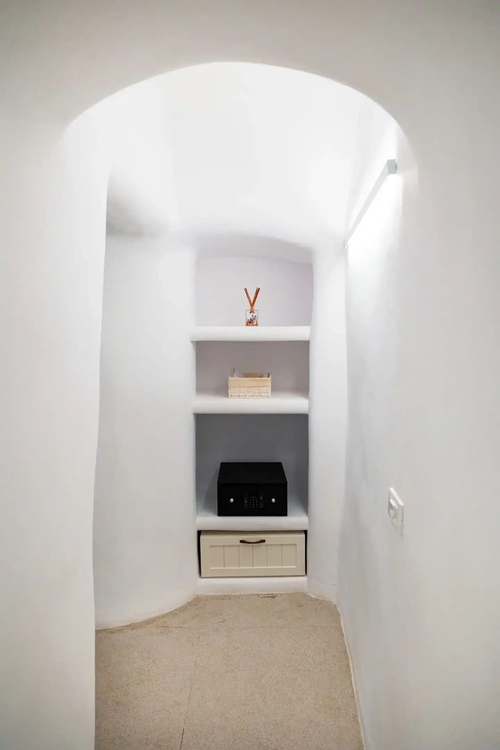 In die weiße Wand eingelassenes Regal mit einem kleinen Safe und Dekoobjekten.
