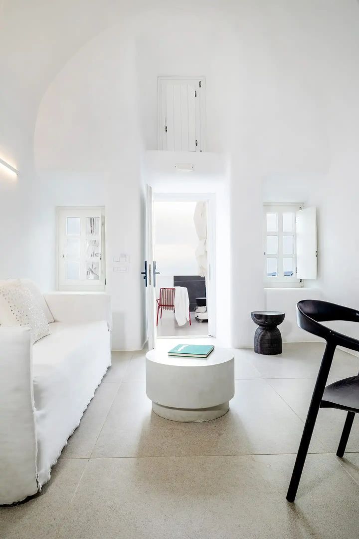 Heller Wohnraum in Weiß mit Sofa, rundem Tisch und Durchgang zur Terrasse.