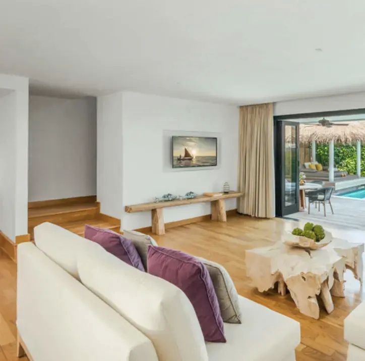 Helles Wohnzimmer mit weißen Sofas, Echtholztisch und Zugang zur Terrasse.