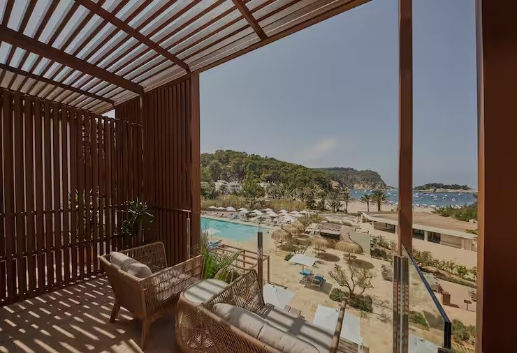 Balkon mit Holzüberdachung und Ausblick auf die Poollandschaft und die Bucht