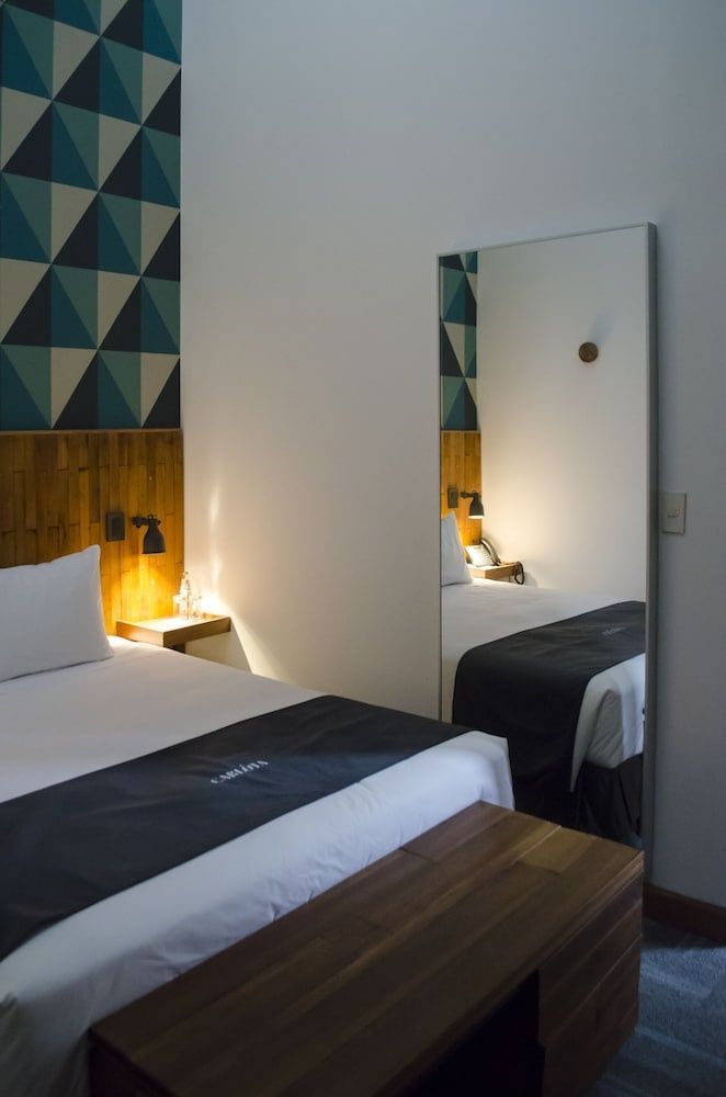 Bett mit grauer Tagesdecke vor Holzwand und blauem Musterdekor