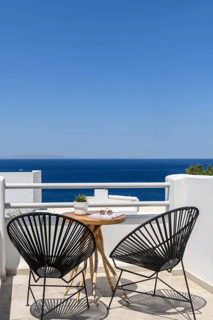 Zwei schwarze Stühle und ein Tisch auf dem Balkon mit direktem Meerblick.
