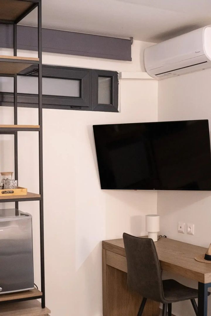 Flachbildfernseher an der Wand über einem kleinen Schreibtisch mit Stuhl im Hotelzimmer.