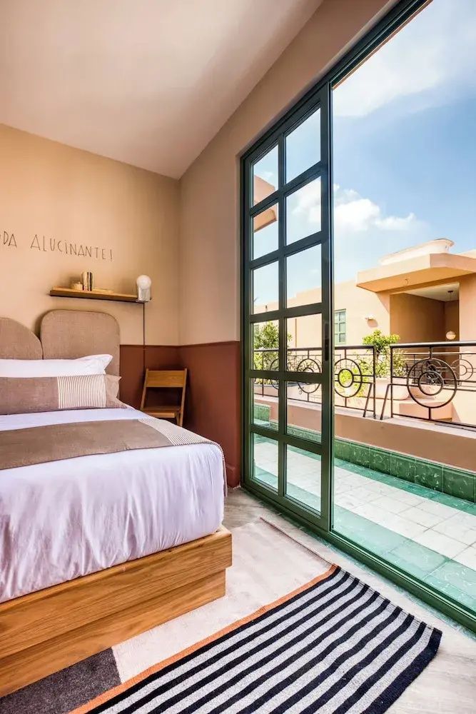 Schlafzimmer mit Doppelbett und großer Glastür zur privaten Terrasse im Außenbereich.