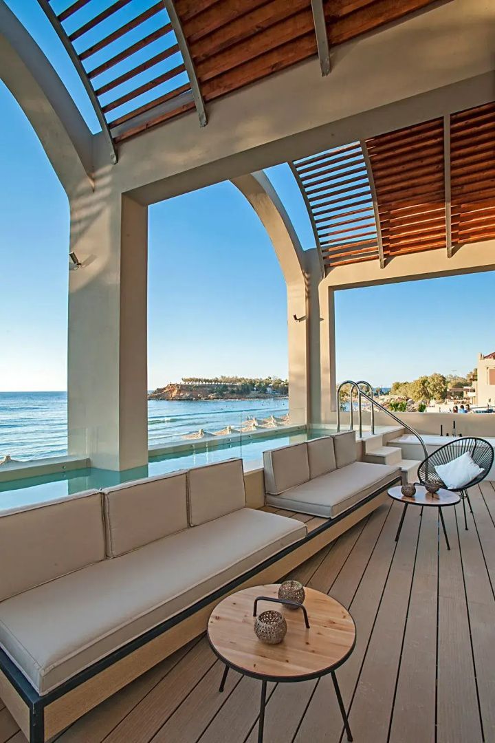 Überdachte Hotelterrasse mit Sitzbank und Privatpool sowie Blick auf das Meeresufer.