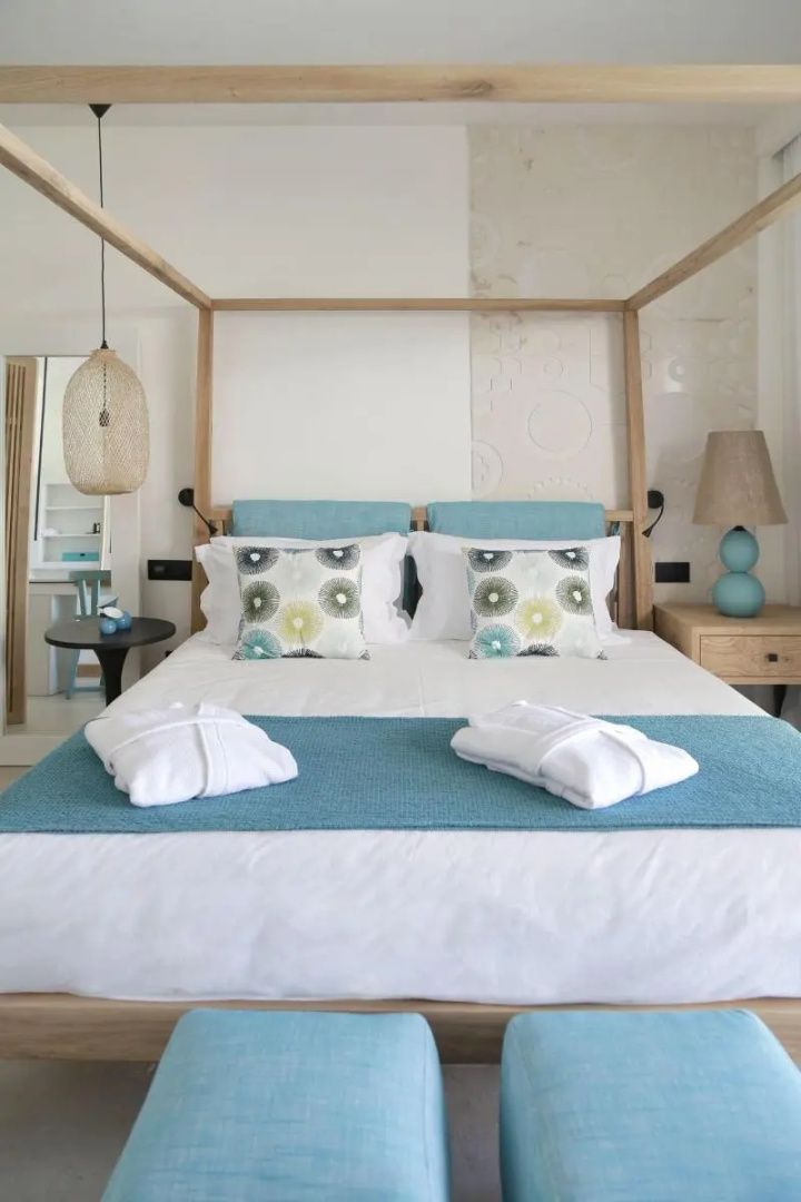 Doppelbett aus Holz mit gemusterten Kissen und blauer Tagesdecke im Zimmer.