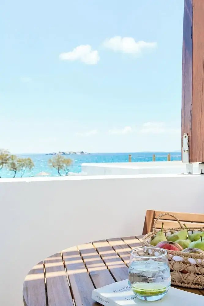 Blick von einer Balkonterrasse auf das blaue Meer unter sonnigem Himmel.