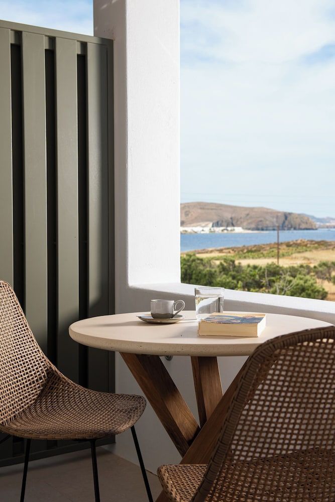 Balkontisch mit Kaffeetasse und Buch bietet Aussicht auf das Meer und die Küstenlandschaft.