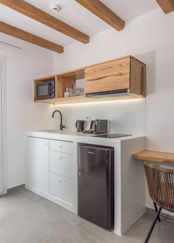 Moderne kleine Küchenzeile mit Kühlschrank, Kaffeemaschine und Regalen aus Holz.