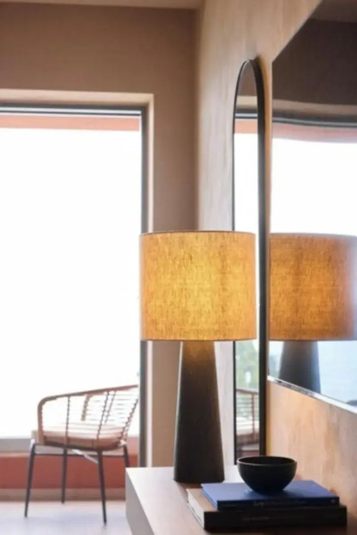 Stehleuchte im Zimmer mit Spiegelung und Blick auf den Balkon im Hintergrund.