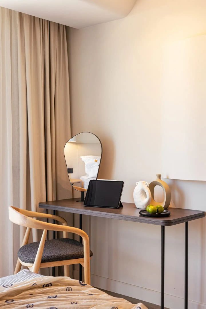 Schreibtisch aus Holz mit Stuhl, Spiegel, Dekoration und einem Tablet im Hotelzimmer.