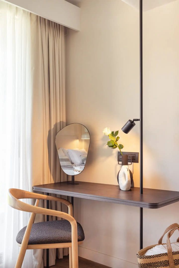Schreibtisch aus Holz mit einem Stuhl, einem kleinen Spiegel und einer Vase mit Rose.