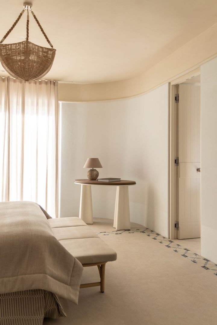 Helles Hotelzimmer mit geschwungener Wand, einem Konsolentisch und Vorhängen.