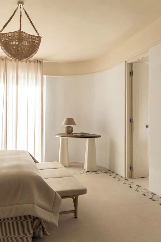 Minimalistisch eingerichtete Ecke eines Hotelzimmers mit beigefarbenem Konsolentisch und Tischlampe.