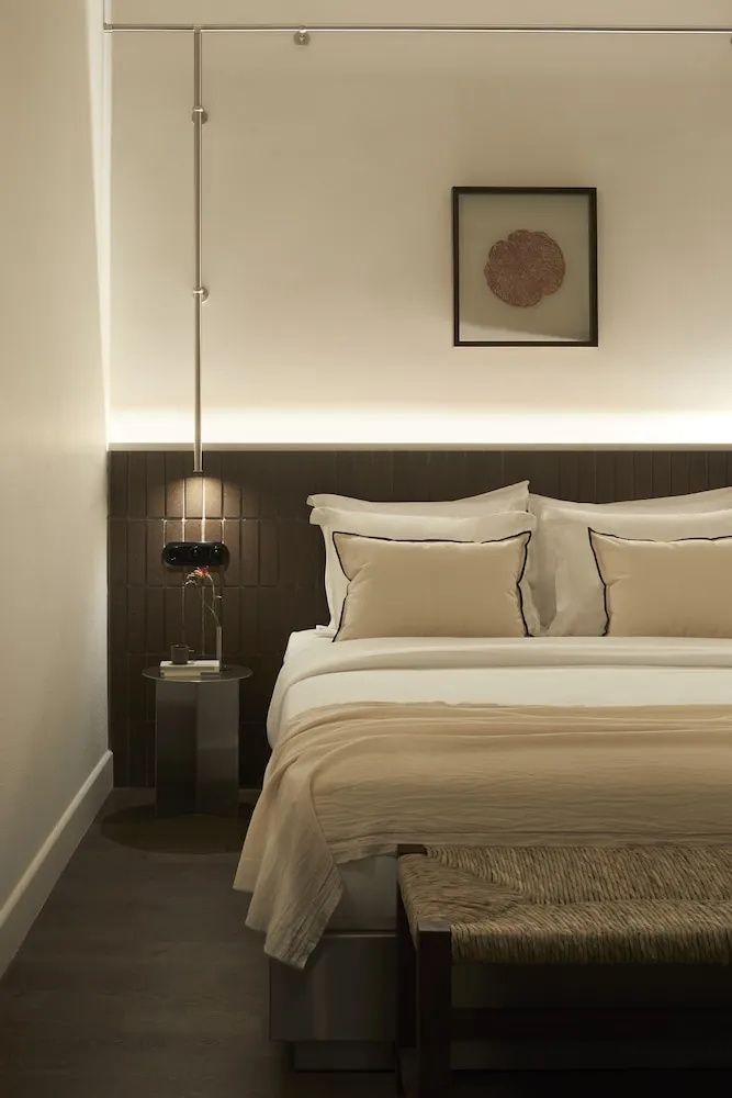 Nahaufnahme eines Doppelbetts mit Hängelampe und kleinem Nachttisch im Hotelzimmer.