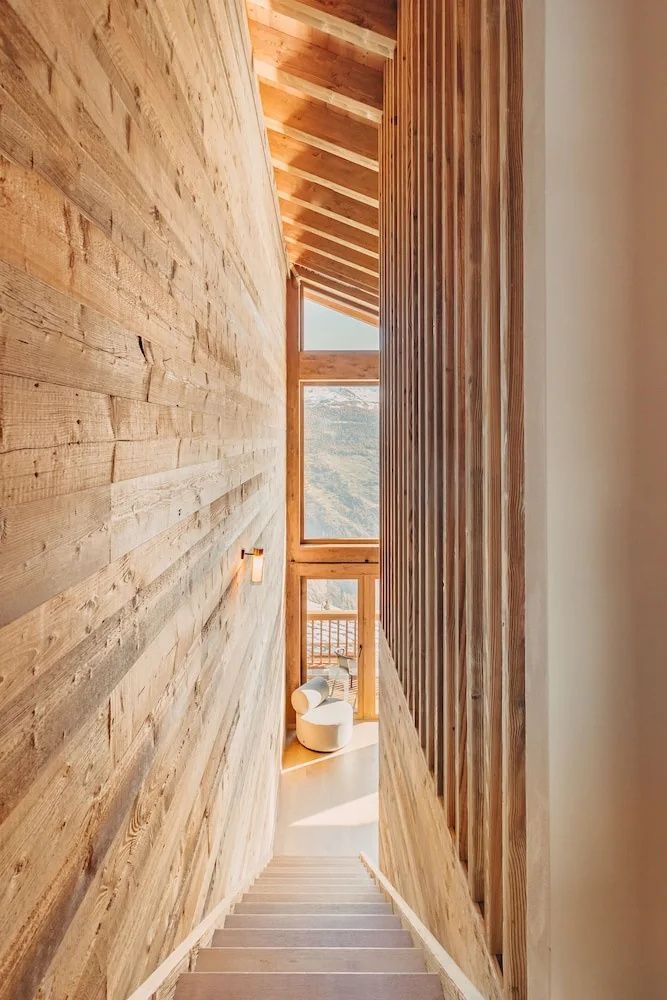 Holzverkleideter Innenraum mit einem hohen Fenster und Blick auf die Berglandschaft.