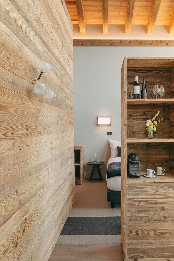 Innenansicht mit Holzvertäfelung, Holzregal mit Kaffeemaschine und Blick auf ein Bett.