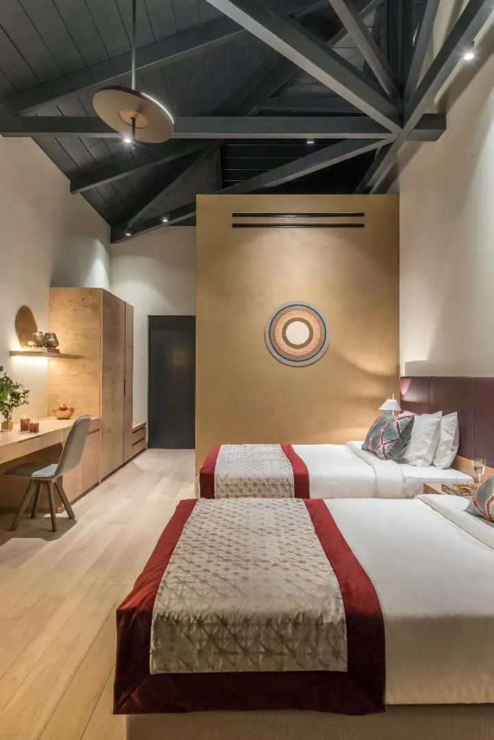 Geräumiges Hotelzimmer mit zwei Einzelbetten, Holzschreibtisch und hoher Decke.