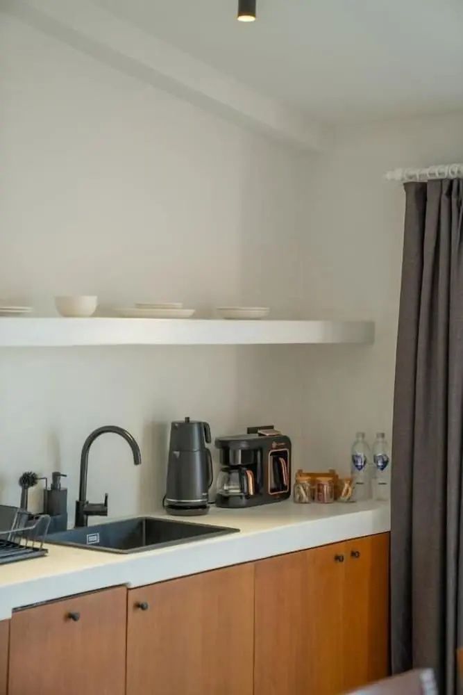 Küchenzeile mit Spülbecken Kaffeemaschine Wasserkocher und offenen Regalen.