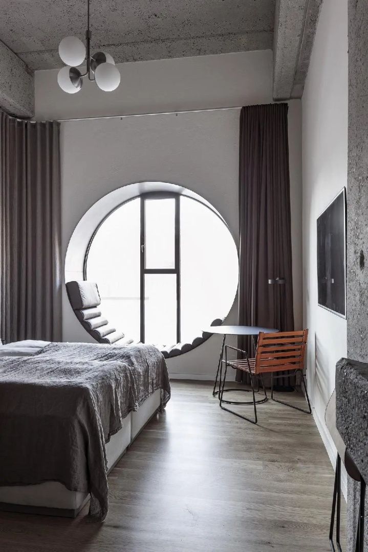 Hotelzimmer mit Doppelbett, rundem Panoramafenster und Sitzgelegenheit.