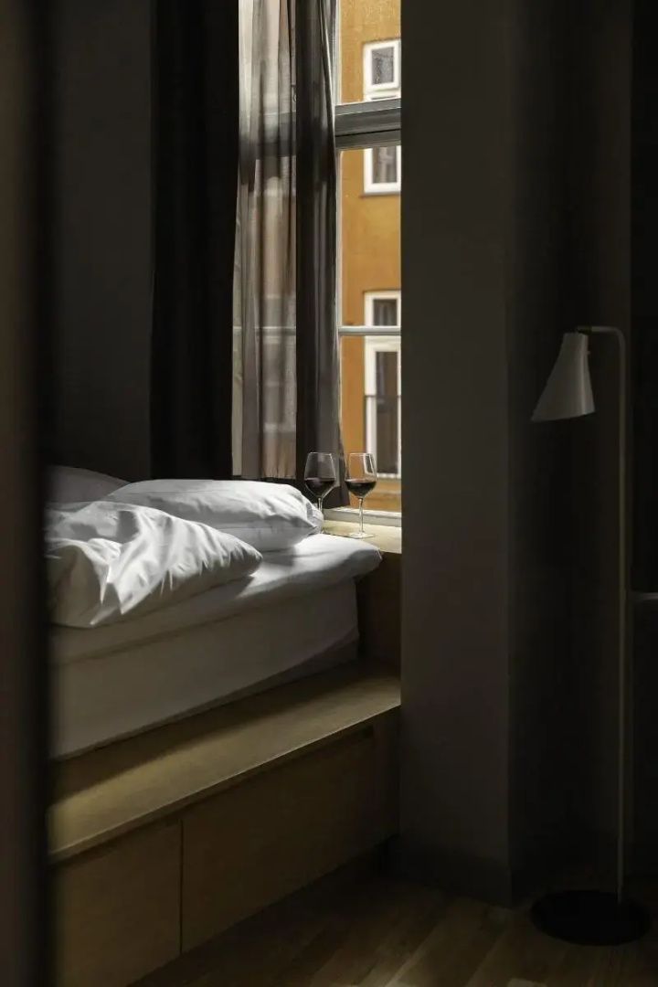 Bettbereich direkt am Fenster mit zwei gefüllten Weingläsern auf der Fensterbank.