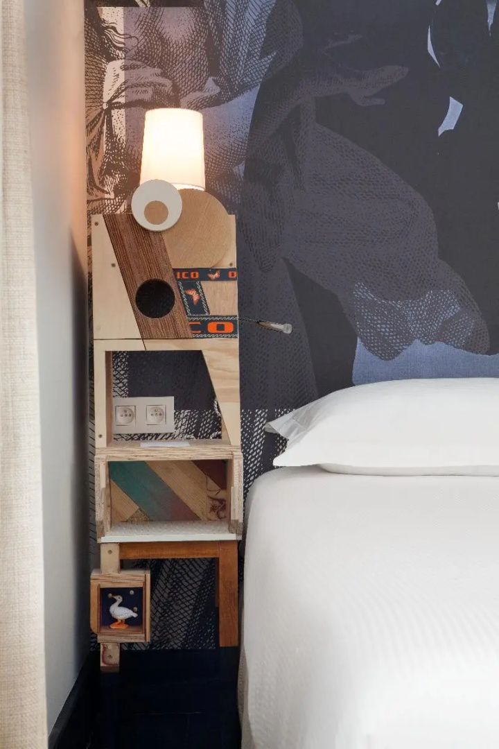 Holz-Nachttisch mit individueller Konstruktion neben einem frisch bezogenen Bett.