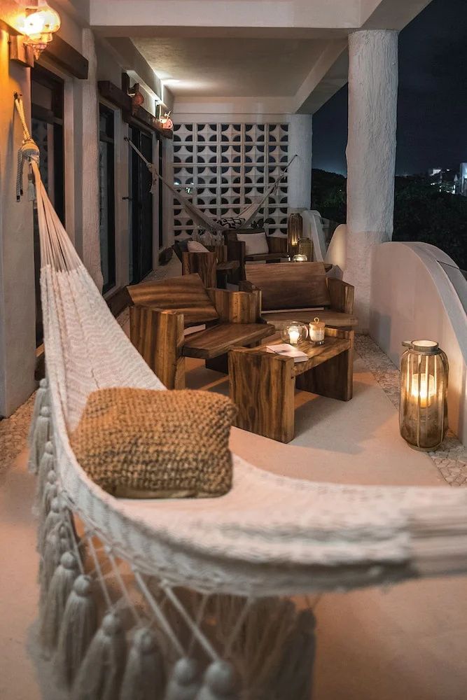 Beleuchtete Terrasse bei Nacht mit einer Hängematte, Holzmöbeln und Laternen.