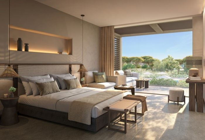Modernes Hotelzimmer mit Doppelbett, Sitzbereich und Terrasse mit Blick ins Grüne.