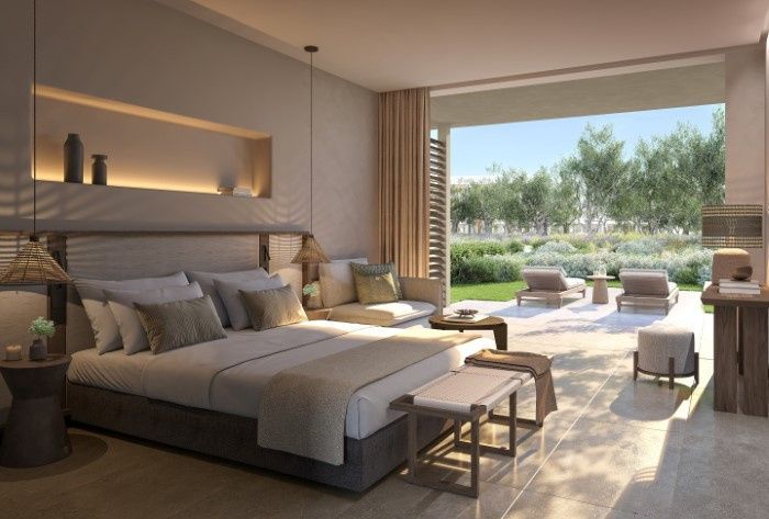 Helles Hotelzimmer mit Doppelbett, Sitzbereich und Übergang zur Sonnenterrasse mit Garten.