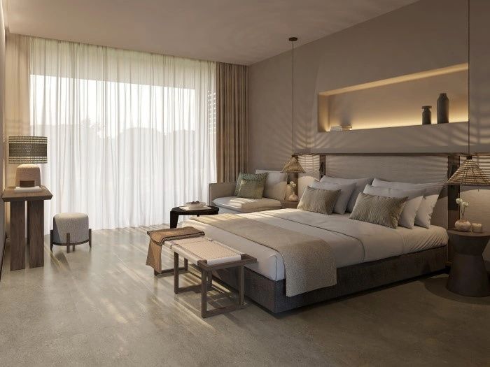 Geräumiges Hotelzimmer mit großem Doppelbett, Sessel und bodentiefen Fenstern.